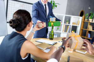 cropped shot of businessman presenting gifts to colleagues in office