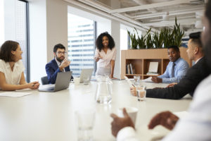 Businesswoman Standing Giving Presentation To Colleagues In Modern Open Plan Office